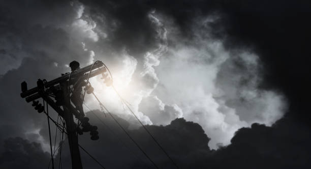Silhouette of electrician working on electric power pole. stock photo