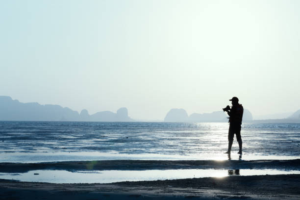 Silhouette of photographer taking picture of landscape during sunset on the beach. stock photo