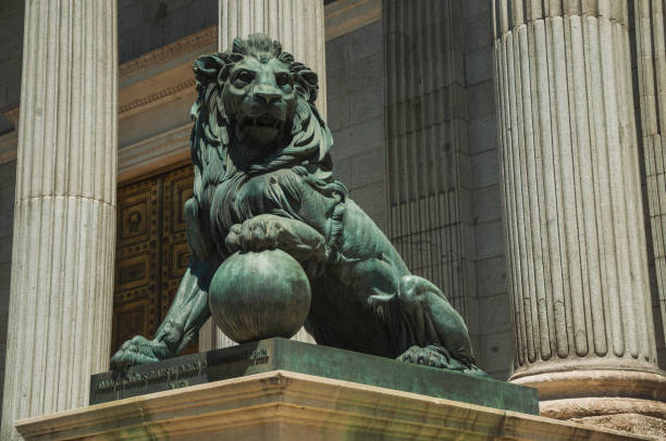 Sculpture of imposing lion cast in bronze on the front facade of Palacio de las Cortes, in a sunny day at Madrid. Capital of Spain this charming metropolis has vibrant and intense cultural life.