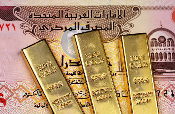 A five dirham bank note from the United Arab Emirates with three small gold bars stock photo