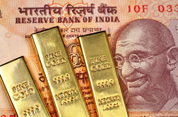 оранжевая десятия индийская рупия с тремя маленькими золотыми слитками - out numbered стоковые фото и изображения
