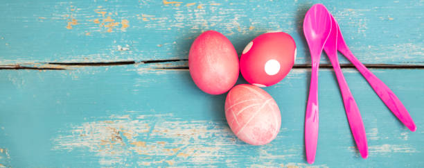 header, three red dyed easter eggs and pink egg spoons on blue wooden background with copyspace - nodoby imagens e fotografias de stock