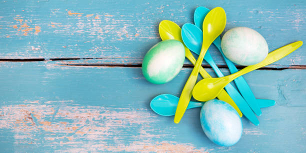 flatlay with copyspace, green and blue dyed easter eggs and spoons on blue shabby chic table - nodoby imagens e fotografias de stock