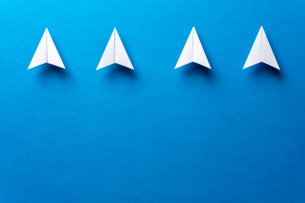 istock Four white paper airplanes, leadership, teamwork, motivation concept on blue background. Paper plane email web message sending. 1133712899