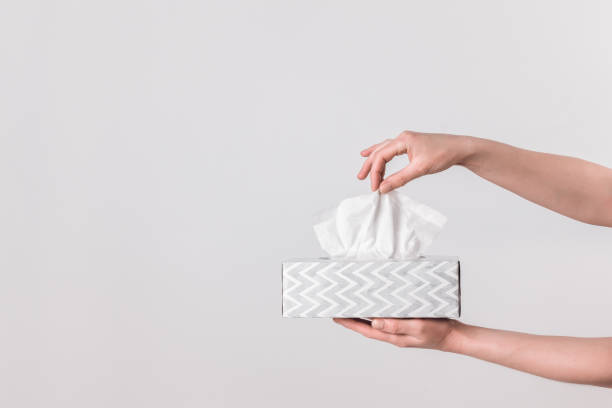 Delicate female hands holding a tissue box Delicate female hands pulling a tissue out of a gray tissue box. facial tissue photos stock pictures, royalty-free photos & images