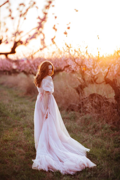 istock Beautiful young girl under the flowering pink tree 1133720021