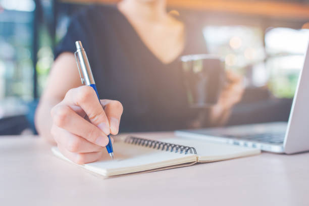 istock Business woman's hand is writing on a notebook with a pen. 1133720198