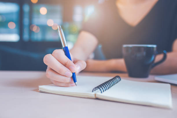 istock Business woman's hand is writing on a notebook with a pen. 1133720200