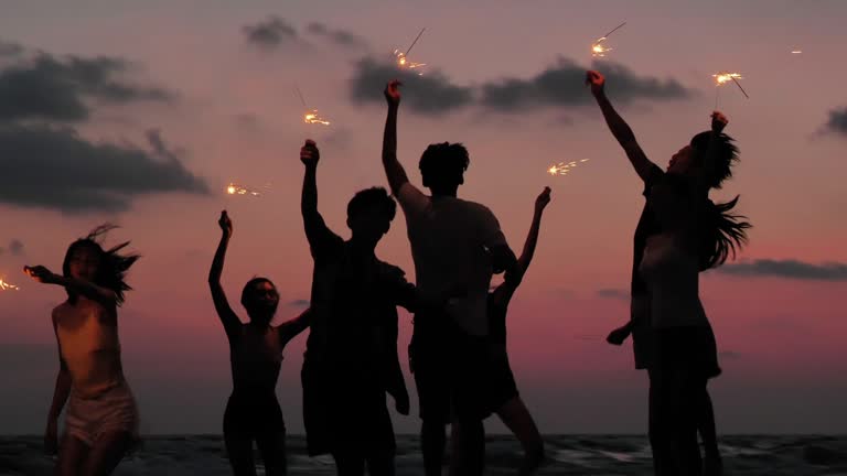 Silhouette of group of friends having fun on the beach with sparklers