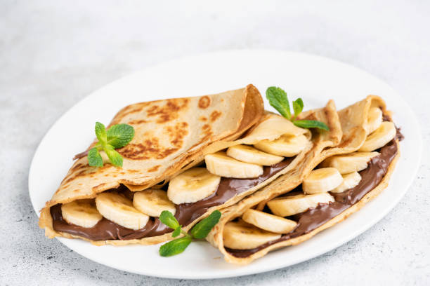 schokoladenhagnüsse und bananen-gefüllte crepes - pancake blini russian cuisine french cuisine stock-fotos und bilder