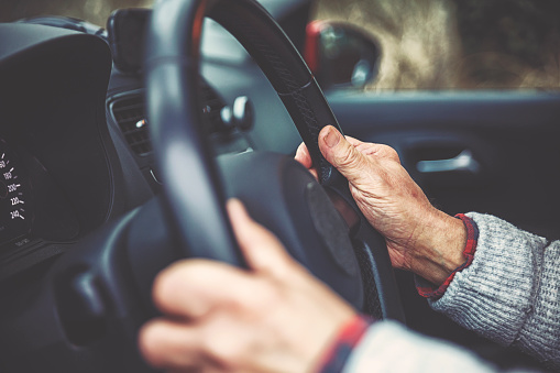 The hand of an elderly gentleman on the steering wheel