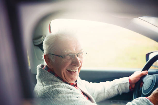 istock Old gentleman drives car and laughs at the camera 1133728865
