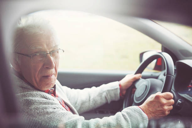 istock Old gentleman drives car and laughs at the camera 1133728872
