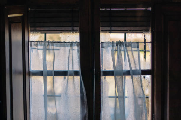 istock Water drops and curtains taking visibility on a window glass from indoor view 1133729954