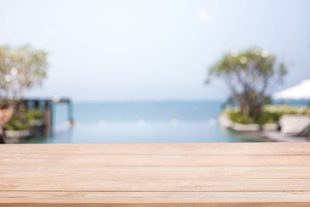 istock Empty  wood table with blur  a luxury infinity swimming pool in the beach hotel. 1133731087
