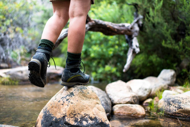 istock Close up of a hiker balancing on a rock next to a river 1133735372