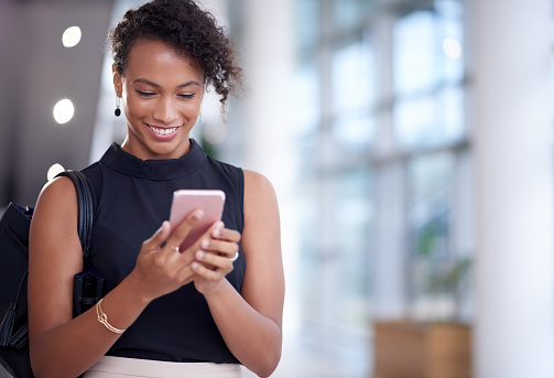 Shot of a young businesswoman using a smartphone in a modern office