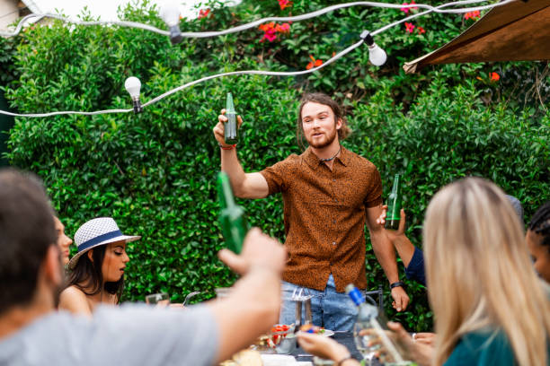 istock Young man with bottle looking away at dinner party 1133742853