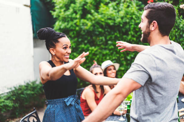 Happy friends embracing in yard at dinner party Happy man and woman embracing while standing at backyard. Friends are enjoying dinner party. They are wearing casuals. reach destination stock pictures, royalty-free photos & images