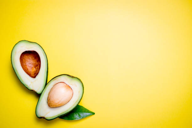 istock Avocado on yellow background. Tropical abstract background with avocado and leaf. Flat lay 1133748120