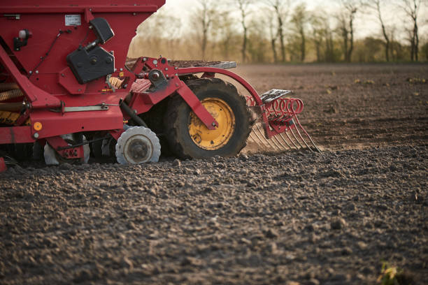 istock Red tractor with sowing machine on a ploughed field 1133749659