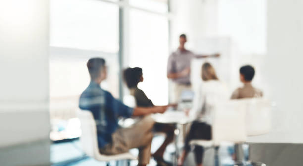 Focus on making a success of the day Defocused shot of a group of businesspeople having a meeting in an office people working together stock pictures, royalty-free photos & images
