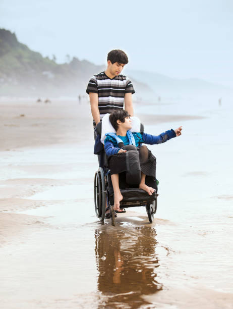 istock Young man pushing disabled brother in wheelchair on beach 1133750717