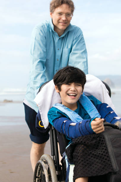 istock Father on beach with disabled son in wheelchair 1133750792