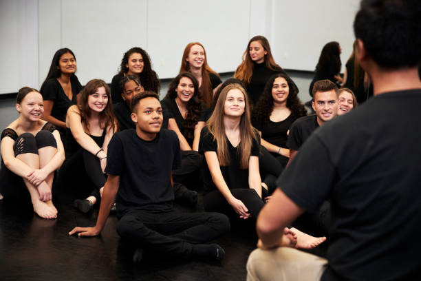 istock Teacher At Performing Arts School Talking To Students Sitting On Floor In Rehearsal Studio 1133752293