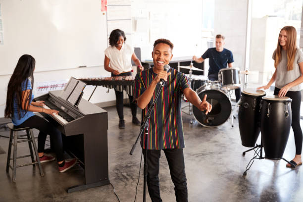 students at performing arts school playing in band at rehearsal with teacher - practicing piano child playing imagens e fotografias de stock