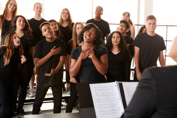 männliche und weibliche schüler singen im chor mit lehrer an der performing arts school - geistliche musik stock-fotos und bilder