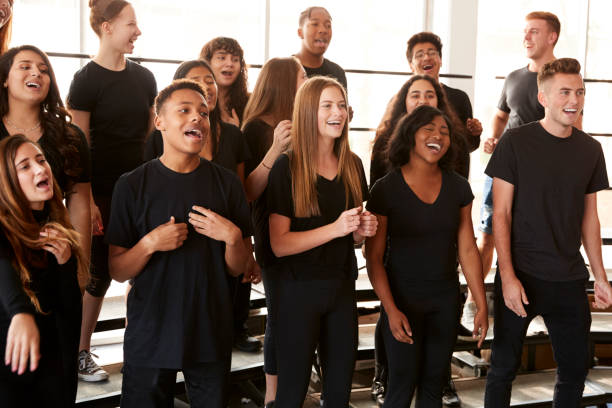 les étudiants masculins et féminins chantant dans le chœur à l'école d'arts de la scène - suing photos et images de collection