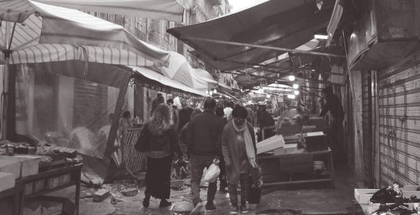 Palermo, Italy - 1st November 2018: People walking and shopping at Ballaro Market. Market vendors standing behind the stalls are also seen in the picture
