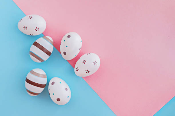 istock Eggs decorated with stripes and flowers on pink and blue background, Easter concept. 1133754486