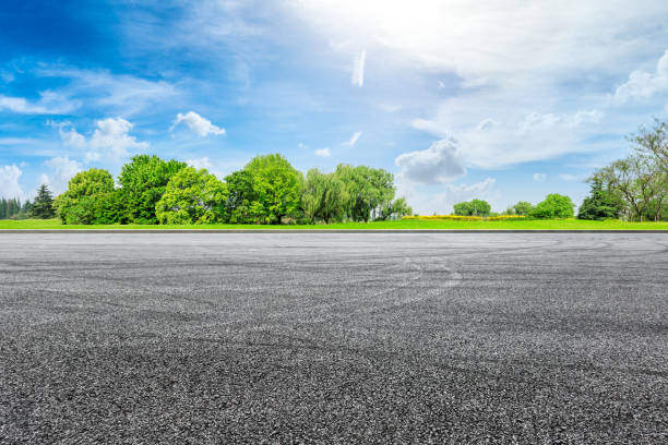 空のアスファルトレーストラックグラウンドと夏の緑の森 - sidewalk ストックフォトと画像