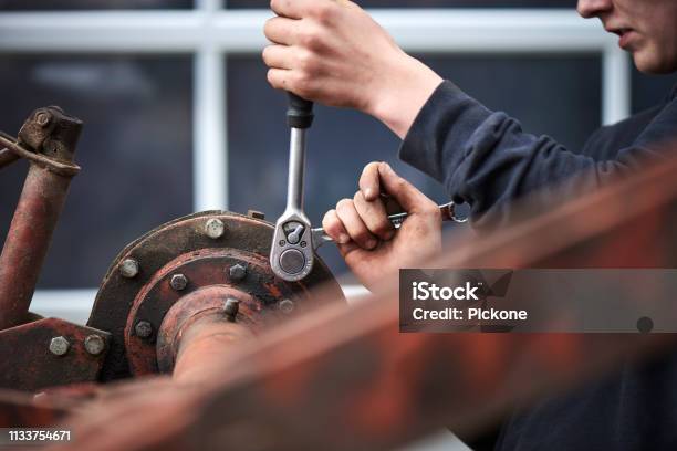 A Young Farmer Repairing Farmer Equipment Stock Photo - Download Image Now - Tractor, Mechanic, Repairing