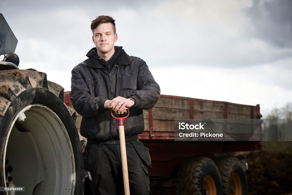 Junger Landwirt vor seinem blauen Traktor - Lizenzfrei Bauernberuf Stock-Foto