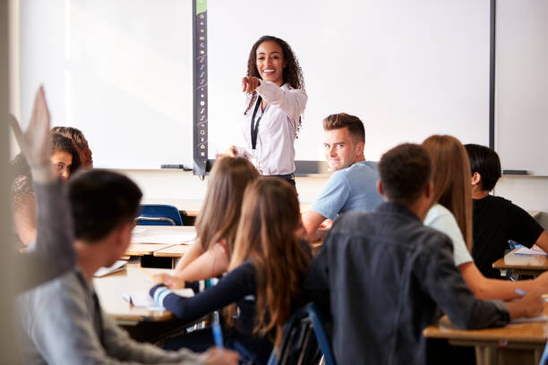 istock Female High School Teacher Asking Question Standing By Interactive Whiteboard Teaching Lesson 1133756551