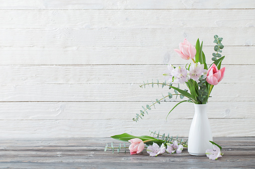 spring flowers in white vase on white wooden background