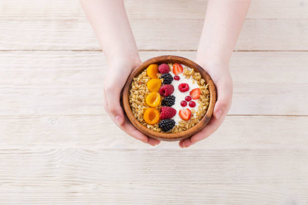 istock granola with berries and hand on white wooden background 1133757369