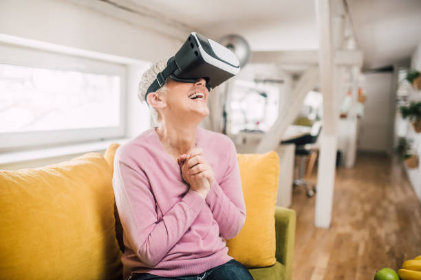 istock Happy mature woman sitting on a couch using a virtual reality simulator 1133757447