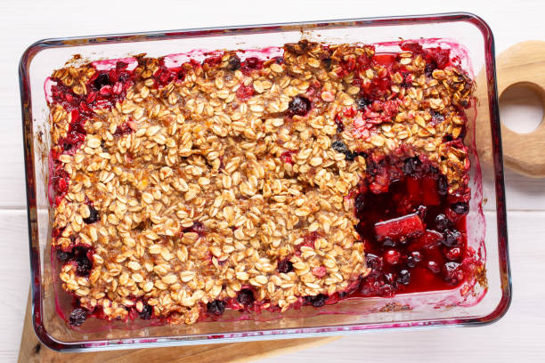 istock Apple and berry crumble, topped with oats in glass baking dish on white table. Crispy fruit pie, healthy summer dessert. Top view, close-up. 1133758760