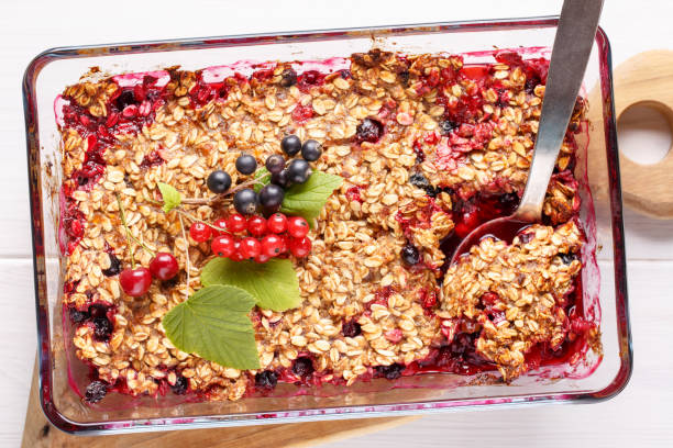istock Apple and berry crumble, topped with oats in glass baking dish on white table. Crispy fruit pie, healthy summer dessert. Top view, close-up. 1133758815