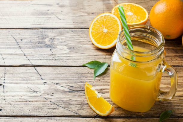 istock Orange juice in glass jars and fresh oranges on a wooden rustic background. Copy space. 1133758976