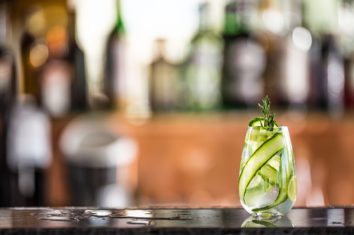 Gin tonic cocktail with cucumber on bar counter in pup or restaurant.