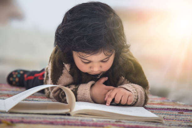 bambina che impara presto a leggere dai libri, sdraiata sulla coperta sul pavimento. concetto di ispirazione educativa. - one baby girl only foto e immagini stock