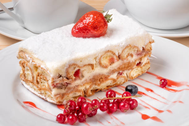 Piece of cake with custard and fresh berries on a white plate.