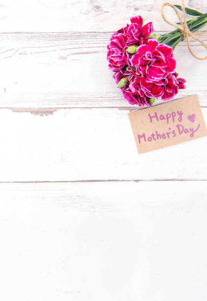 istock May mothers day concept photography - Beautiful carnations with template card isolated on a bright wooden table, copy space, flat lay, top view, mock up 1133763161