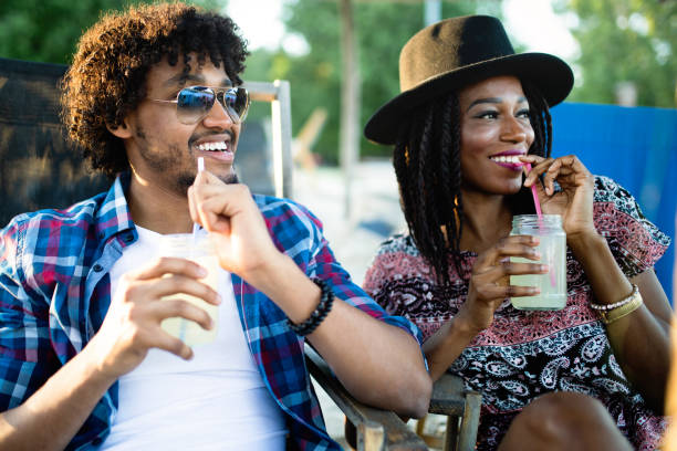 istock Young happy black couple with drinks relaxing on the beach 1133767226