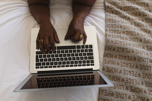 High angle view of senior African American woman typing on laptop in bedroom at home